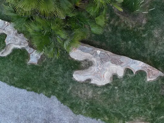 Vista do alto de rochas esculturais e palmeiras sobre o gramado